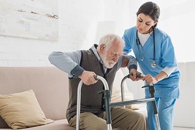 Nurse helping elderly gentleman with walker
